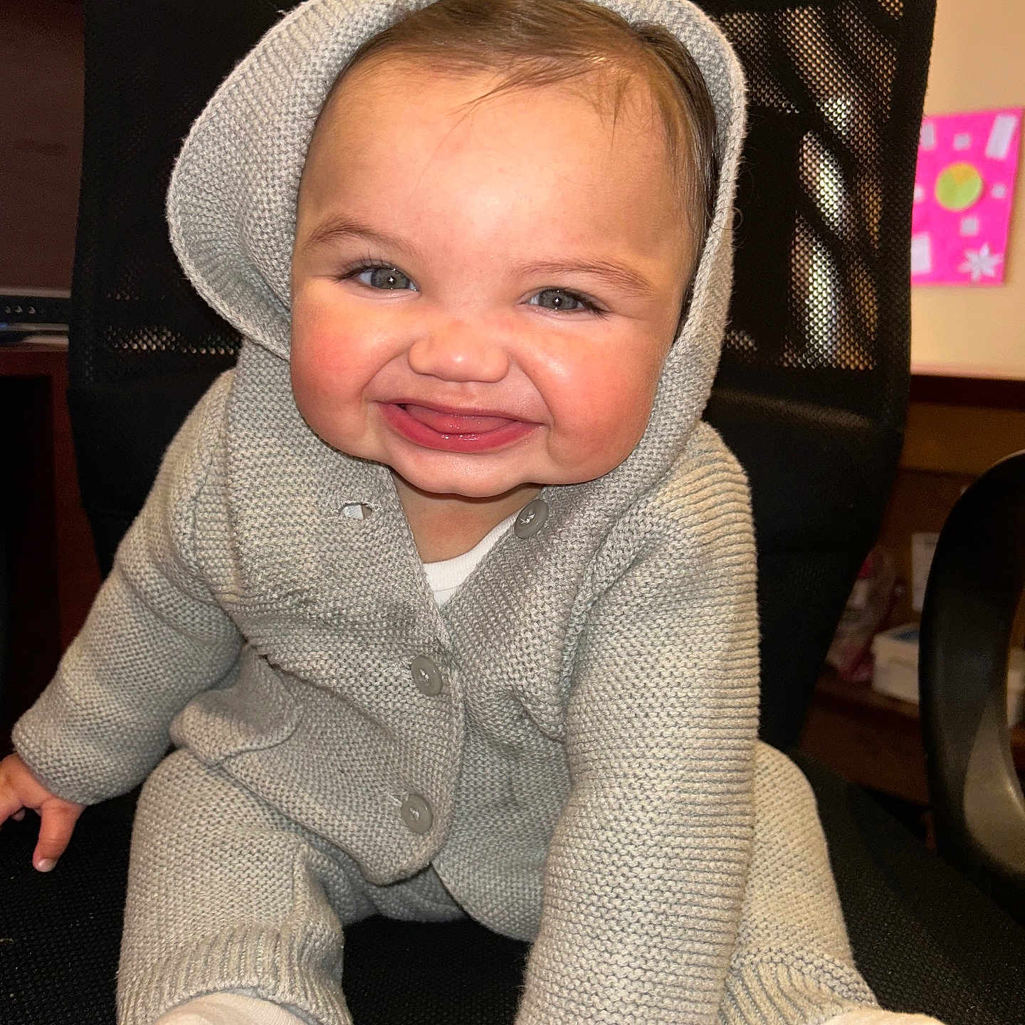 Stori joined the competition — help win amazing prizes! baby, child, smile, hooded_sweater, knitwear, gray_clothing, sitting, indoor, chair, mesh_chair, happy, cute, infant, person, feet, white_socks, face, portrait, room, background