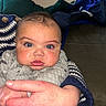 Stori is registered to the contest to win money with this photo: baby, blue_eyes, infant, hand, cozy_clothing, knitted_sweater, couch, indoor, portrait, cute, chubby_cheeks, person, child, holding, face, eyelashes, skin, expression, closeup, warmth