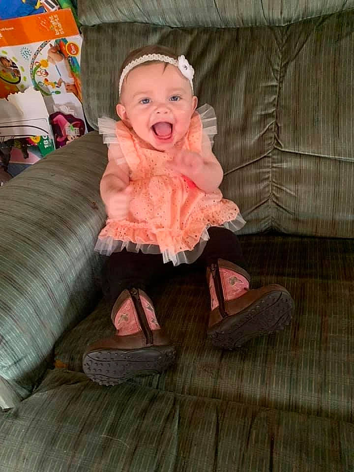 Avery is registered to the contest to win money with this photo: baby_toddler_clothing, cheek, comfort, couch, dress, fashion_accessory, flooring, fun, fur, hardwood, human_body, lap, magenta, peach, person, sitting, sleeve, smile, toddler, wood