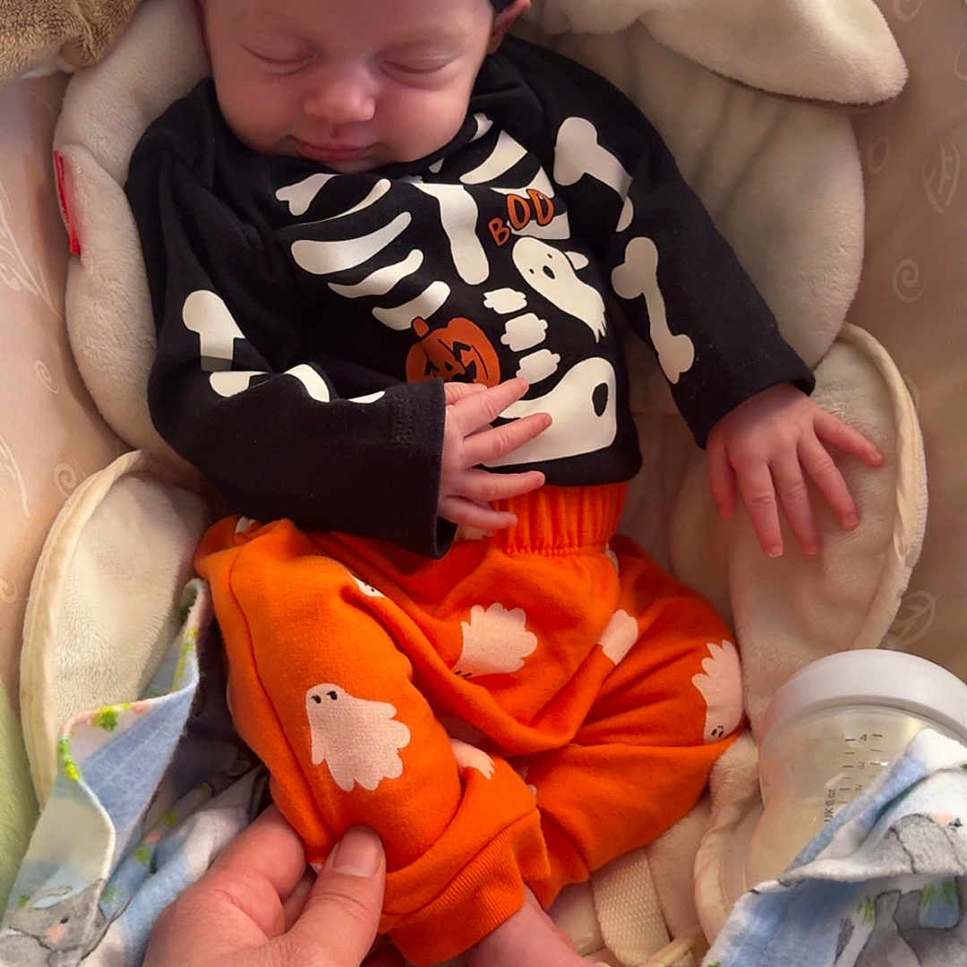 Liliana joined the competition — help win amazing prizes! baby, baby_seat, black_headband, blanket, bottle, clothing, comfort, cozy, cute, foot, ghost_print, hand, infant, orange_pants, pearl, pumpkin, resting, skeleton_outfit, sleeping, tattoo