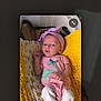 baby, infant, blanket, pink_outfit, headband, dinosaur_print, knitted, yellow_blanket, white_socks, lying_down, indoors, portrait, child, cute, small, soft_texture, cozy, newborn, baby_clothes, resting