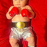 baby, boxing_gloves, championship_belt, silver_shorts, black_boots, red_background, infant, portrait, boxing, costume, child, cute, serious_expression, lying_down, indoor, red, small_person, sportswear, funny, adorable
