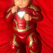 Kailas joined the competition — help win amazing prizes! baby, infant, costume, iron_man, superhero, red, fabric, lying_down, child, face, person, portrait, cute, small, hands, feet, bright, colorful, soft, clothing