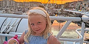 Nina a rejoint le concours — aidez-le/la à gagner de superbes lots ! child, girl, doll, toy, sunset, ferris_wheel, marina, boat, water, handrail, sky, clouds, headband, blonde_hair, clothing, pose, outdoor, smile, portrait, evening