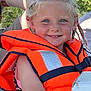 Nina a rejoint le concours — aidez-le/la à gagner de superbes lots ! child, smile, life_jacket, braids, outdoor, tree, nature, sunlight, boat, summer, blue_eyes, happy, person, water_safety, daytime, casual_clothing, portrait, closeup, fun, vacation