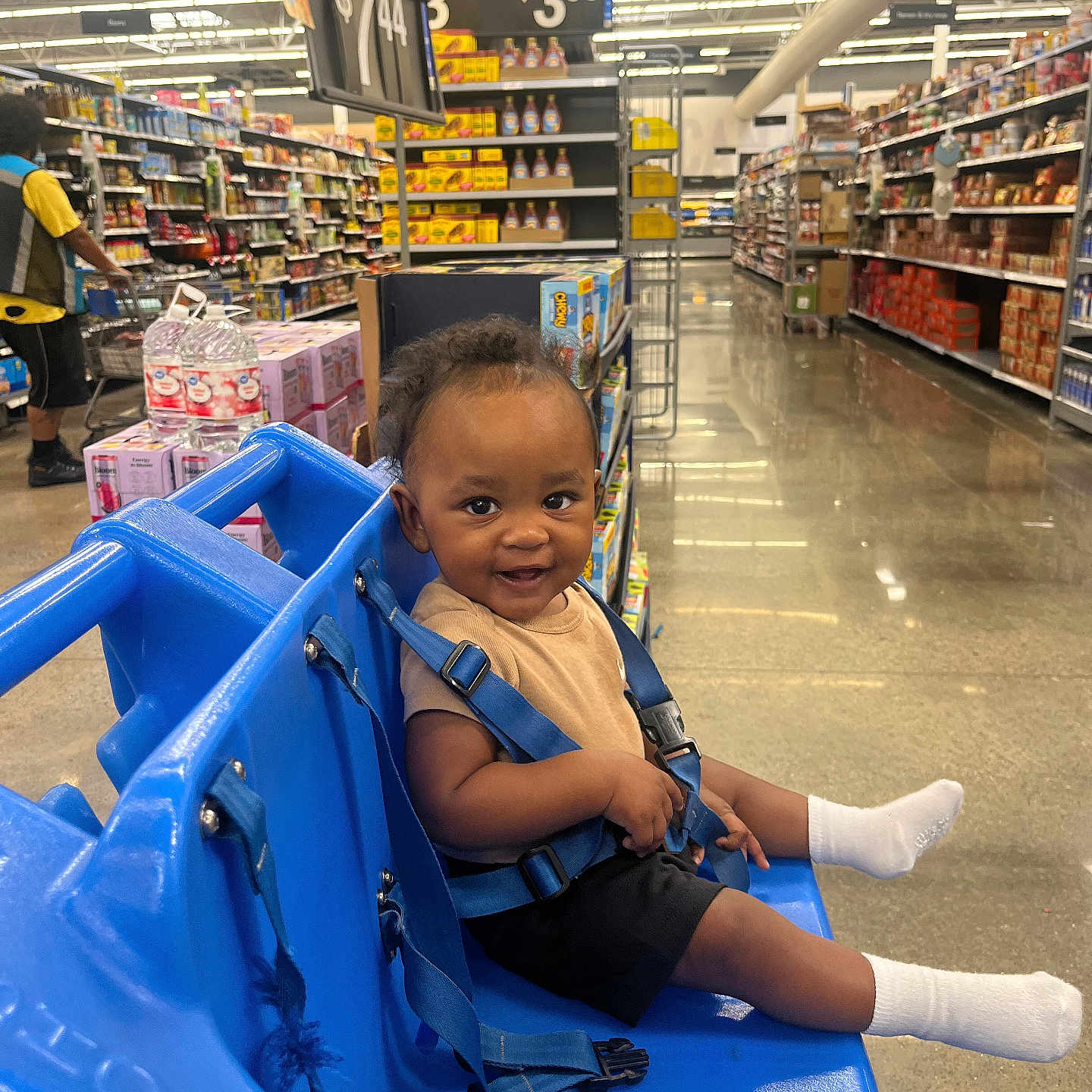 Janari is registered to the contest to win money with this photo: aisle, blue, child, clothing, floor, grocery_store, happy, indoor, light, person, products, retail, seatbelt, shelf, shopping, shopping_cart, smile, socks, store, toddler