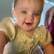 Sabine is registered to the contest to win money with this photo: baby, child, smiling, face, dress, cream_color, indoor, close_up, cute, happy, person, portrait, young_child, short_hair, bright_eyes, soft_lighting, fabric_texture, infant, toddler, apparel