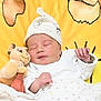 newborn, baby, sleeping, plush_toy, lion, hat, blanket, yellow, white_clothing, cute, infant, child, peaceful, soft_toy, resting, indoors, portrait, closeup, baby_hand, cozy