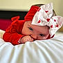Hanaë participe au concours pour gagner de l'argent avec cette photo : baby, infant, headband, bow, red_clothing, white_bow, heart_pattern, lying_down, soft_surface, portrait, close_up, cute, child, indoors, face, hand, skin, eyes, baby_girl, focus