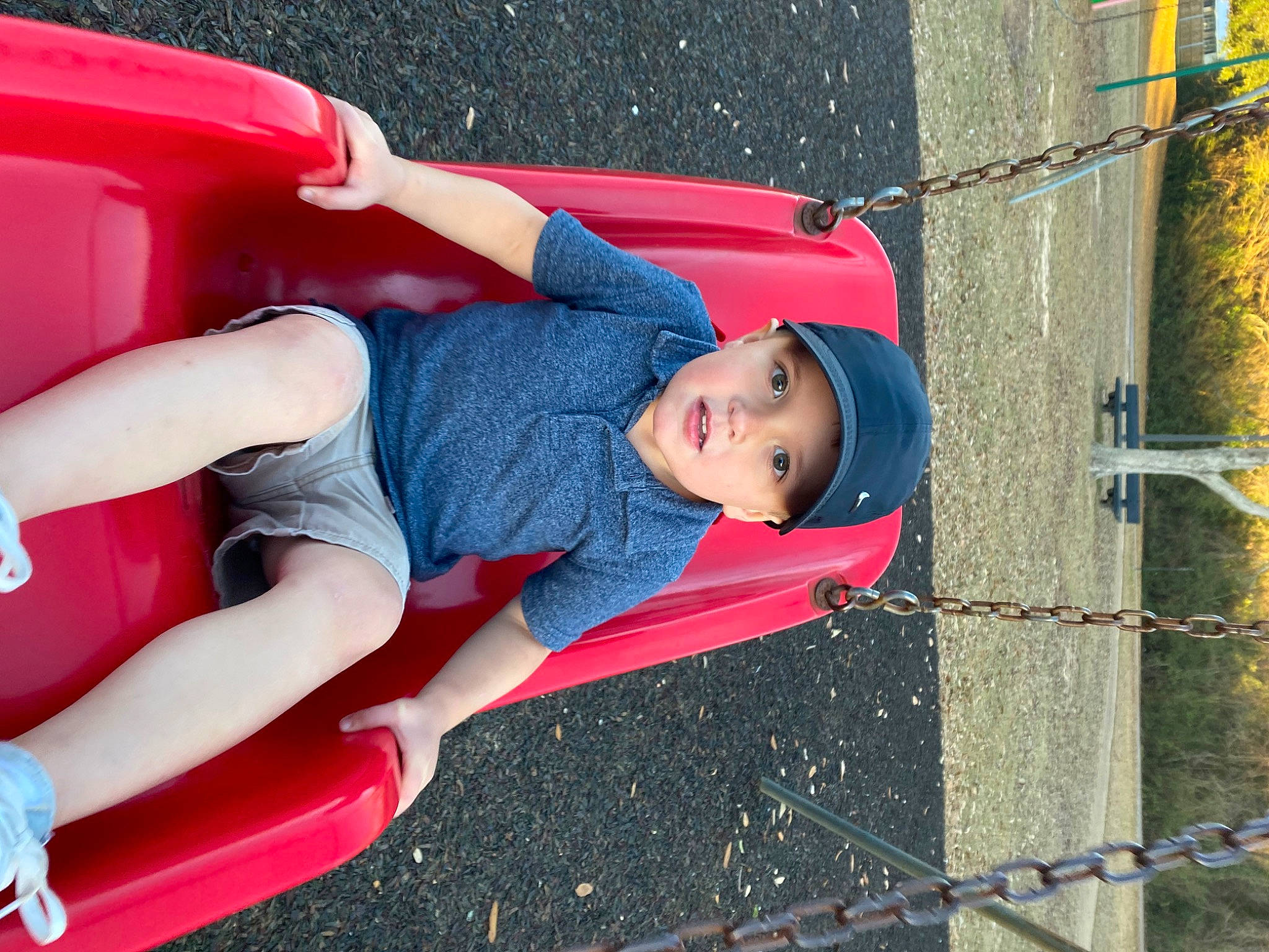 Lyle is registered to the contest to win money with this photo: child, electric_blue, fence, fun, headwear, human_body, leg, leisure, mesh, outdoor_play_equipment, person, play, playground, public_space, recreation, red, shorts, smile, snapshot, toddler