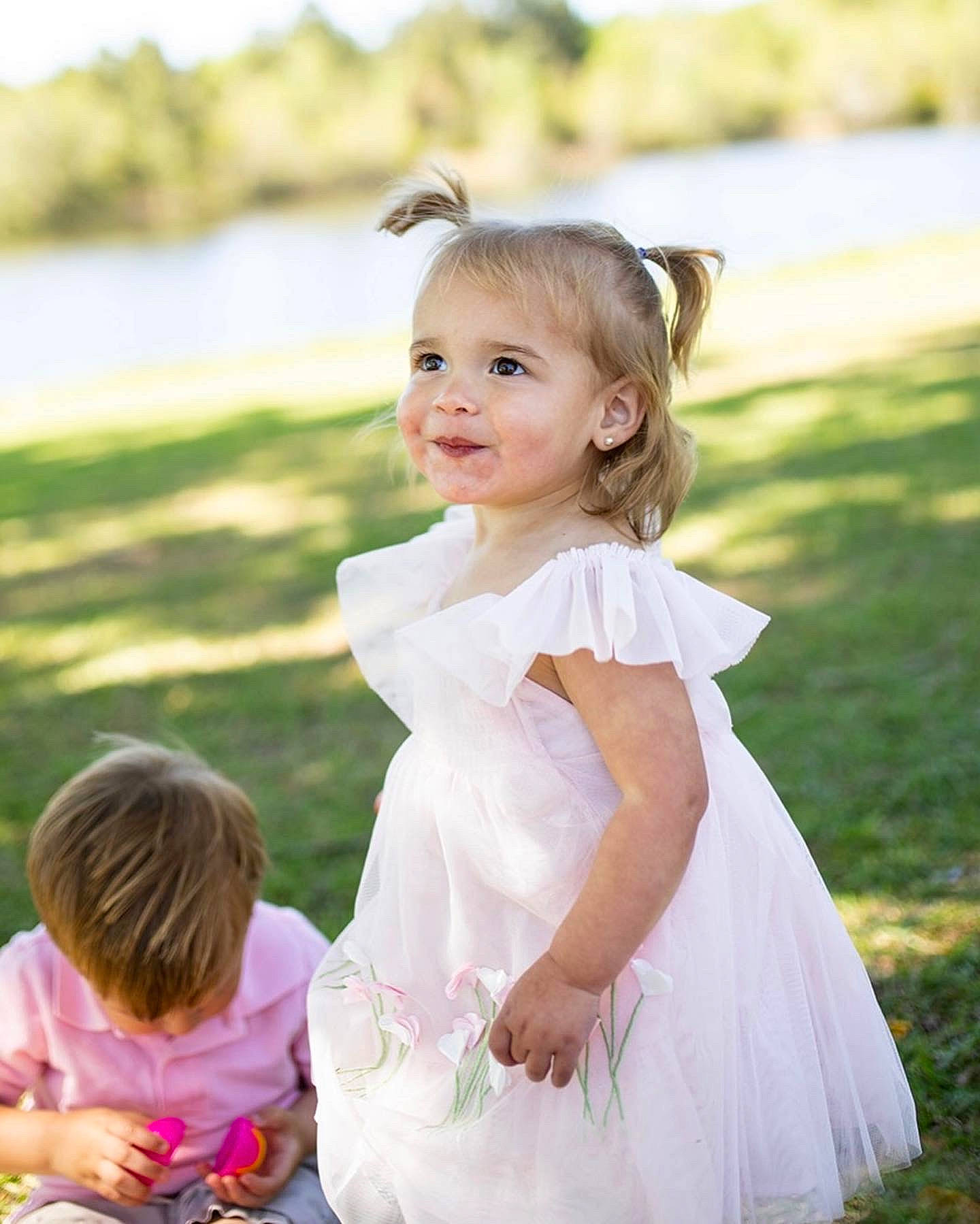 Laura is registered to the contest to win money with this photo: baby, blond, bridal_accessory, bridal_clothing, bridal_party_dress, child, dress, event, fashion_accessory, formal_wear, fun, gesture, gown, grass, happy, joy, person, pink, recreation, smile