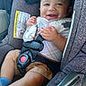 baby, car_seat, child, smiling, safety_harness, seatbelt, clothing, fabric, warning_label, cute, infant, hands, legs, blue_sock, happy, seat, interior, comfort, portrait, closeup