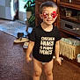 Levi is registered to the contest to win money with this photo: child, boy, indoor, black_shirt, novelty_glasses, smile, carpet, cabinet, plant, slippers, home, furniture, diaper, happy, cute, clothing, person, standing, decor, toy_glasses