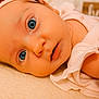 baby, infant, blue_eyes, headband, bow, pink_clothing, floral_pattern, blanket, close_up, face, skin, portrait, cute, newborn, lying_down, soft_texture, child, indoors, expression, person
