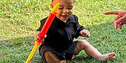 Leander joined the competition — help win amazing prizes! toddler, child, grass, toy, outdoor, happy, playing, sitting, person, casual_clothing, hand, greenery, daylight, smiling, barefoot, fun, leisure, summer, young_child, playtime