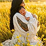 woman, baby, infant, field, yellow_flowers, tattoo, white_dress, sunlight, nature, outdoor, portrait, love, mother, child, peaceful, grass, warm_light, holding, smile, relaxation
