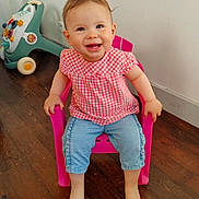 Romane participe au concours pour gagner de l'argent avec cette photo : toddler, child, smiling, pink_chair, checkered_shirt, blue_pants, barefoot, wooden_floor, toy_car, indoor, happy, sitting, cute, person, baby, furniture, playful, casual_clothing, head, face