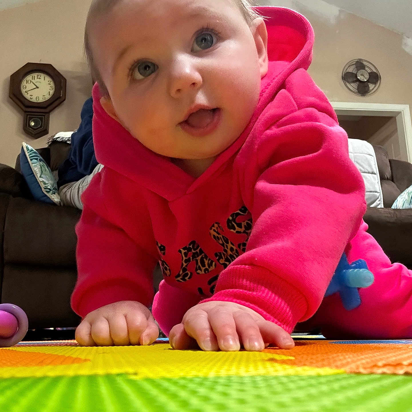 Raynie joined the competition — help win amazing prizes! baby, child, crawling, hoodie, pink_clothing, play_mat, indoor, carpet, hands, face, blue_eyes, curious, cute, person, toddler, floor, toy, home, living_room, expression