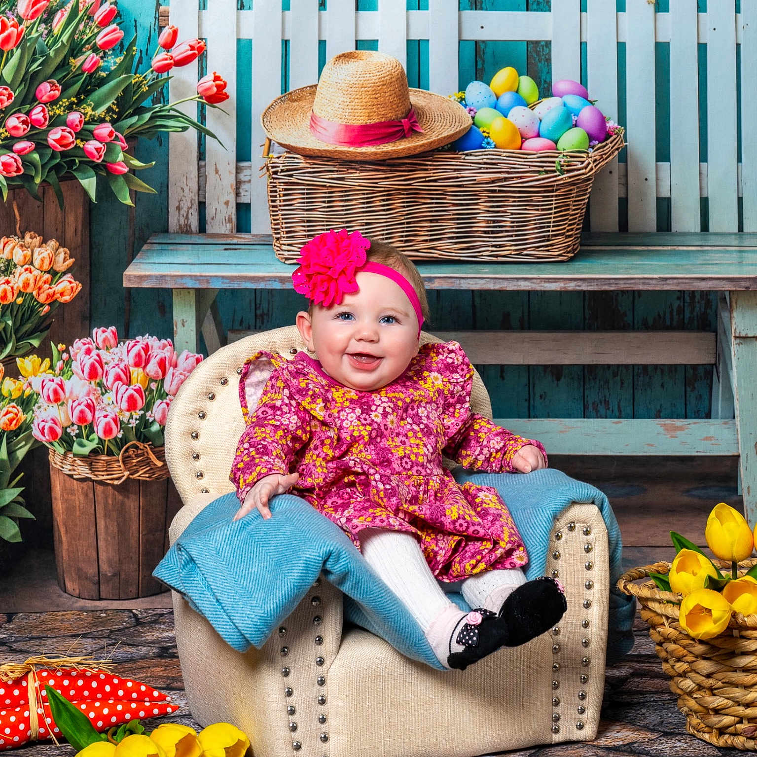 Raynie joined the competition — help win amazing prizes! baby, child, infant, pink_headband, floral_dress, armchair, blue_blanket, tulips, yellow_tulips, basket, easter_eggs, straw_hat, wooden_bench, white_picket_fence, stone_floor, spring, smiling, indoors, portrait, happy