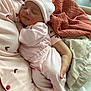 baby, newborn, sleeping, pink_clothing, hat, blanket, arm, hand, caregiver, bed, soft_fabric, comfort, peaceful, indoor, person, infant, rest, cute, tender, cozy