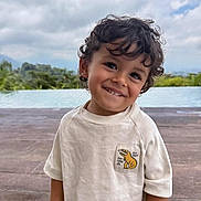 Maël participe au concours pour gagner de l'argent avec cette photo : child, smile, curly_hair, shirt, dinosaur_patch, outdoor, pool, nature, greenery, sky, cloudy, portrait, happy, cute, young, boy, casual_clothing, daytime, background, playful