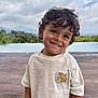child, smile, curly_hair, shirt, dinosaur_patch, outdoor, pool, nature, greenery, sky, cloudy, portrait, happy, cute, young, boy, casual_clothing, daytime, background, playful