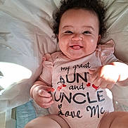 Evanaley is registered to the contest to win money with this photo: baby, infant, child, smiling, tongue_out, curly_hair, portrait, lying_down, bed, blanket, pink_clothing, onesie, ruffles, sunlight, indoors, happy, family_message, face, hands, photography