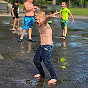 Parker is registered to the contest to win money with this photo: child, children, playground, water, splash_pad, barefoot, jeans, summer, outdoor, fun, park, wet, play, boys, greenery, laughing, casual_clothing, joy, active, friends