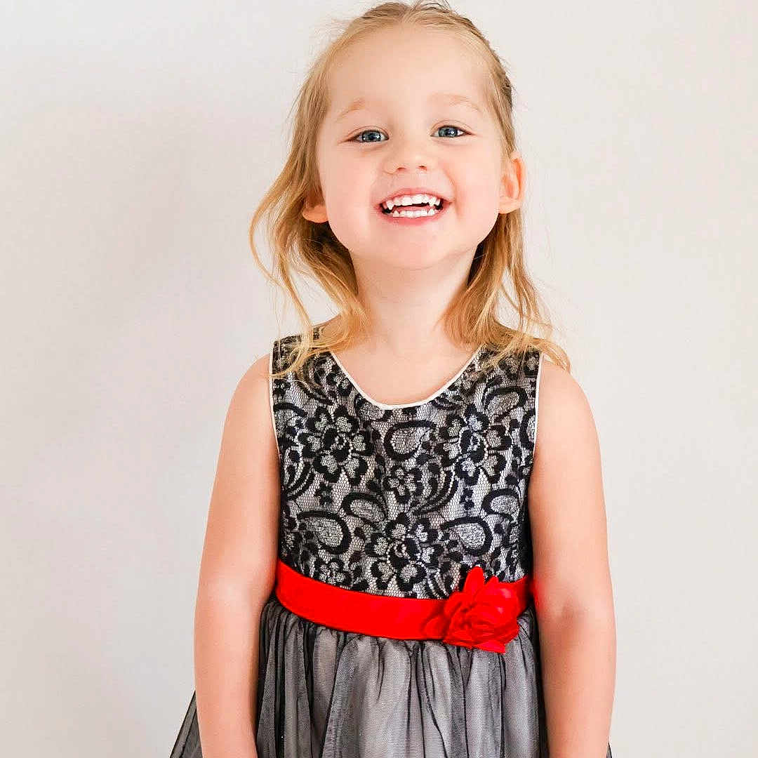 Harley joined the competition — help win amazing prizes! background, black_lace, blonde_hair, bright, cheerful, child, cute, dress, fashion, flower, girl, happy, innocent, portrait, pose, red_sash, smile, standing, studio, young