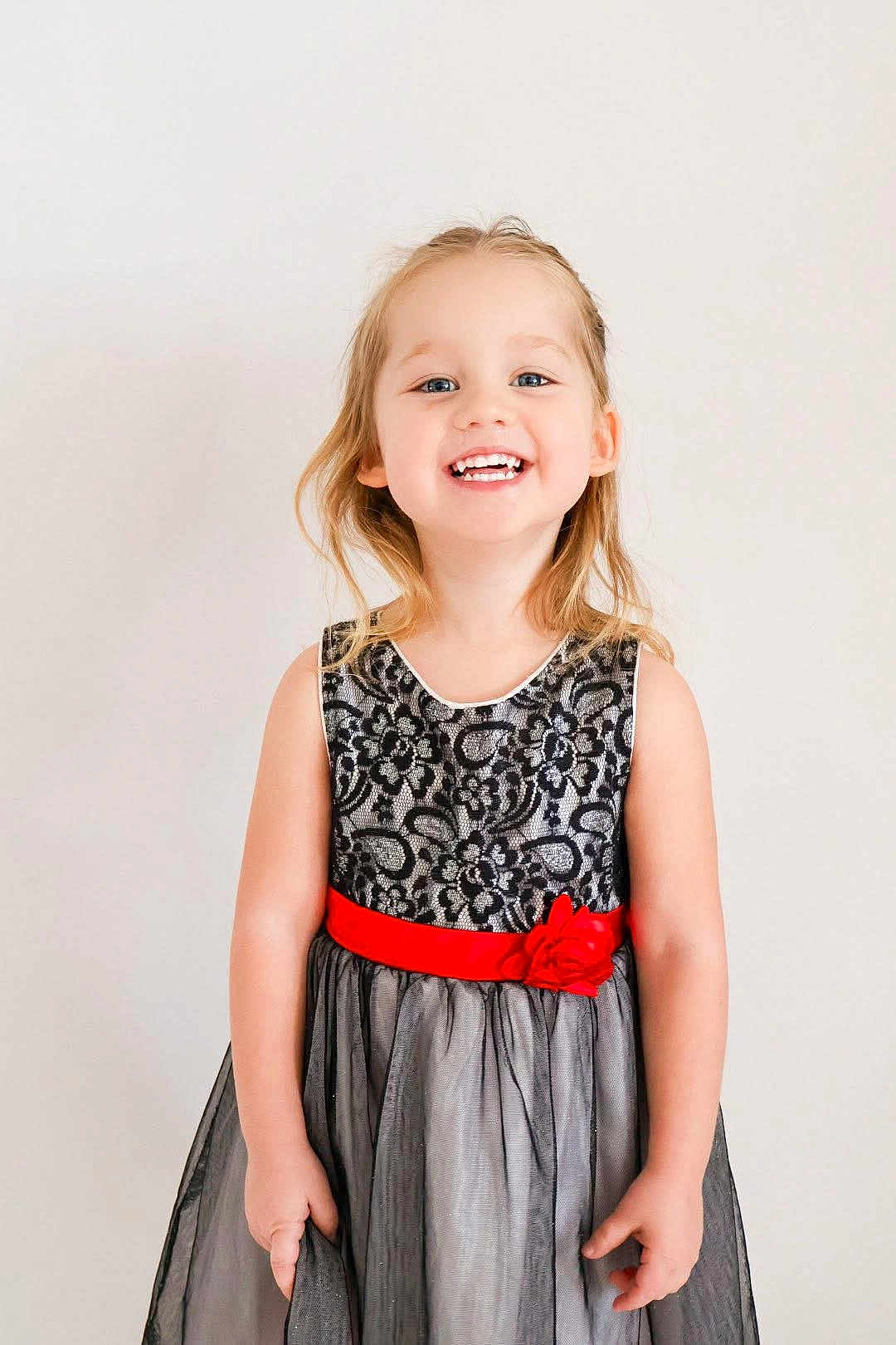 Harley joined the competition — help win amazing prizes! background, black_lace, blonde_hair, bright, cheerful, child, cute, dress, fashion, flower, girl, happy, innocent, portrait, pose, red_sash, smile, standing, studio, young