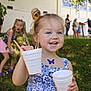 background, blue_dress, butterfly_sticker, child, daylight, event, fun, girl, grass, happy, holding, nature, outdoor, people, plastic_cups, play, portrait, smiling, summer, sunlight