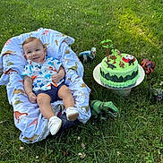 Emmanuel joined the competition — help win amazing prizes! baby, infant, grass, outdoor, toy_dinosaur, birthday_cake, dinosaur_theme, blanket, smiling, child, shoes, shirt, nature, greenery, celebration, happy, sitting, playful, cute, summer
