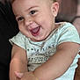 arm, baby, blurred_background, bracelet, child, closeup, cute, expression, face, hands, happy, holding, human, indoor, infant, person, shirt, skin, smiling, young
