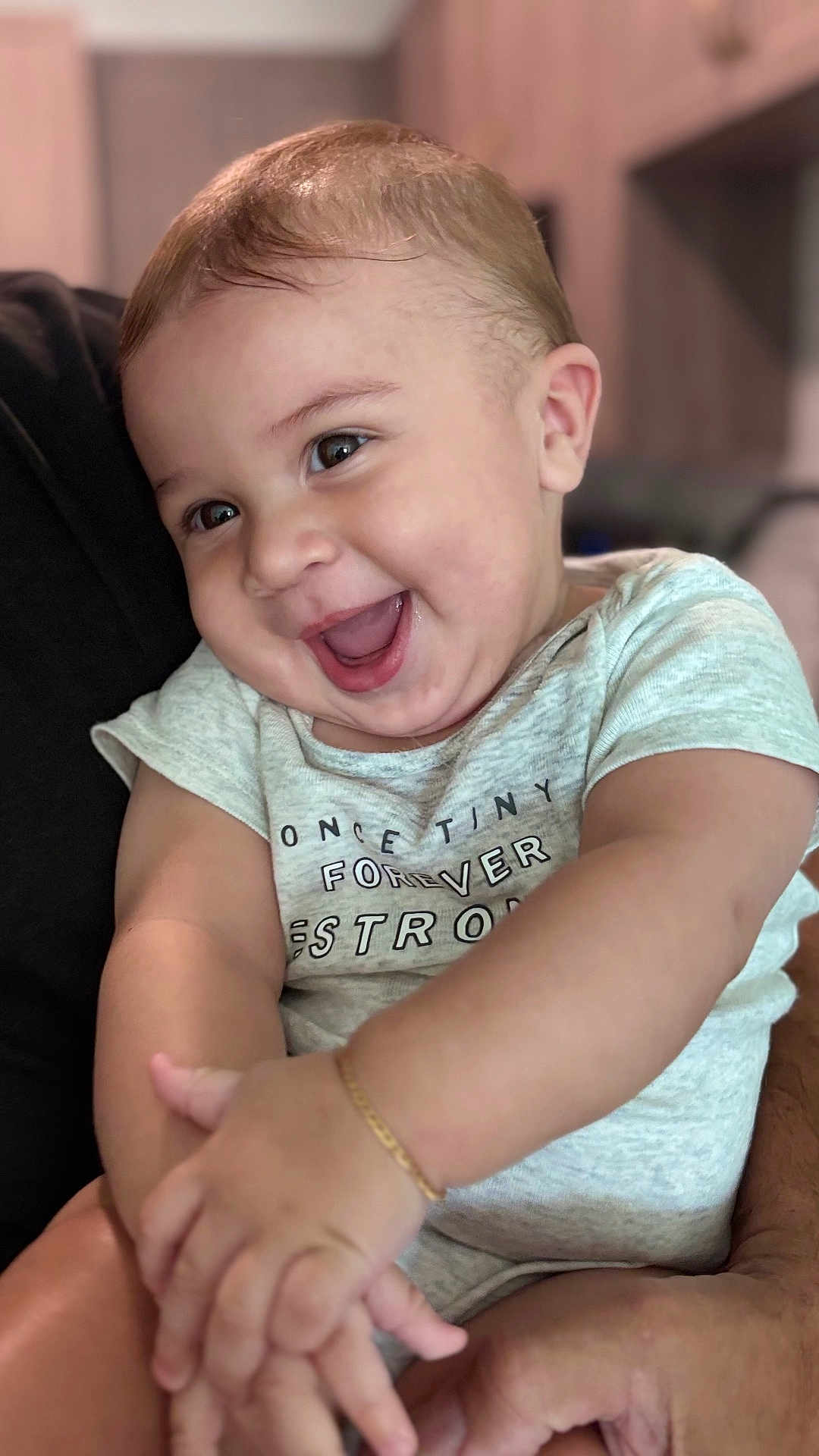 Matteo Fernandes is registered to the contest to win money with this photo: arm, baby, blurred_background, bracelet, child, closeup, cute, expression, face, hands, happy, holding, human, indoor, infant, person, shirt, skin, smiling, young