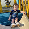 Domenick joined the competition — help win amazing prizes! child, toddler, slide, playground, yellow, blue, sneakers, shirt, shorts, outdoor, sunlight, smiling, play_structure, handrail, grass, park, person, face, recreation, fun