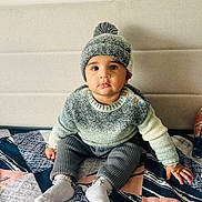 Gurfateh Singh is registered to the contest to win money with this photo: baby, bracelet, carpet, child, cozy, curious, cute, floor, home, indoor, infant, knit_hat, neutral_background, patterned_rug, portrait, seated, socks, soft_lighting, sweater, warm_clothing