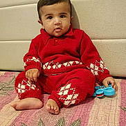 Gurfateh Singh joined the competition — help win amazing prizes! baby, child, red_clothing, knitwear, toy, blue_toy, sitting, floor, patterned_mat, indoor, cute, infant, portrait, face, barefoot, hand, head, person, young_child, cozy