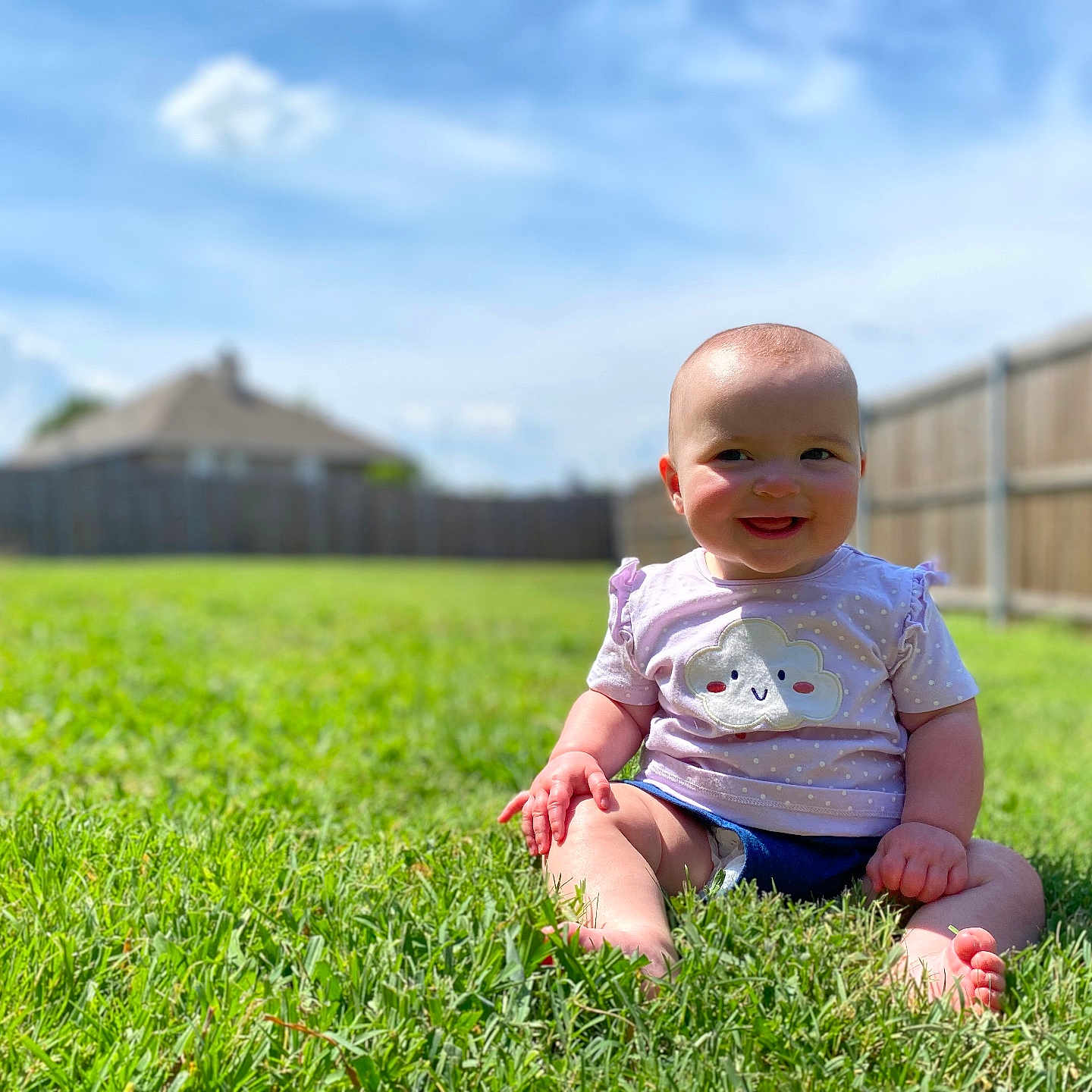 Olivia joined the competition — help win amazing prizes! baby, backyard, clothing, face, field, grass, grassland, happy, head, lawn, nature, outdoors, person, photography, plant, portrait, shorts, sitting, summer, yard