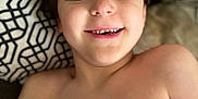 Jonah is registered to the contest to win money with this photo: child, boy, smiling, face, head, shirtless, pillow, couch, indoor, happy, young, skin, hair, expression, closeup, portrait, relaxing, casual, comfortable, home