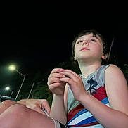 Jonah joined the competition — help win amazing prizes! child, boy, night, outdoor, streetlight, casual_clothing, shorts, sleeveless_shirt, looking_up, hands, skin, legs, hair, person, young, contemplative, dark_sky, nature, evening, lighting