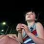 child, boy, night, outdoor, streetlight, casual_clothing, shorts, sleeveless_shirt, looking_up, hands, skin, legs, hair, person, young, contemplative, dark_sky, nature, evening, lighting