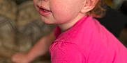 Loralye is registered to the contest to win money with this photo: toddler, child, pink_shirt, face, eyes, cheeks, curious, indoor, blanket, pattern, leaning, person, portrait, young_child, skin, hair, candid, expression, close_up, casual