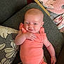 Daniela is registered to the contest to win money with this photo: baby, infant, onesie, peach, couch, cushion, smile, hand, face, relaxing, indoor, soft_furnishing, baby_gear, blanket, comfort, child, person, home, cute, resting