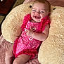 baby, infant, smiling, pink_dress, fluffy_cushion, blanket, happy, skin, face, child, cute, laying_down, indoors, soft_texture, legs, arm, expression, comfortable, cheerful, toddler