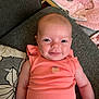 baby, infant, smile, face, arm, clothing, couch, pillow, fabric, pink, coral, person, indoor, seat, baby_seat, soft_toy, head, skin, cute, happy