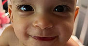 Zemira is registered to the contest to win money with this photo: baby, blanket, child, closeup, crib, cute, expression, eyes, face, happy, head, human, indoor, infant, person, portrait, skin, smiling, toddler, young