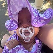 Zemira is registered to the contest to win money with this photo: baby, child, floral_pattern, hand, hat, nature, outdoor, pacifier, parent, person, pillar, purple_clothing, relaxation, rest, shade, sidewalk, skin, sleeping, summer, sunlight