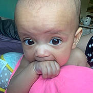 Zemira is registered to the contest to win money with this photo: baby, blanket, child, closeup, curious, expression, face, fist, hand, head, home, indoors, infant, large_eyes, lying_down, person, pink, room, skin, soft