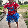 Zemira joined the competition — help win amazing prizes! child, toddler, barefoot, sidewalk, outdoor, grass, trees, red_shirt, blue_tutu, stars, smiling, person, clothing, sky, electric_pole, residential_area, happy, cute, summer, nature