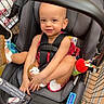 baby, car_seat, child, child_seat, cute, footwear, grocery_store, happy, indoor, infant, person, red_outfit, safety, seat, shopping_cart, smiling, straps, supermarket, toddler, toy